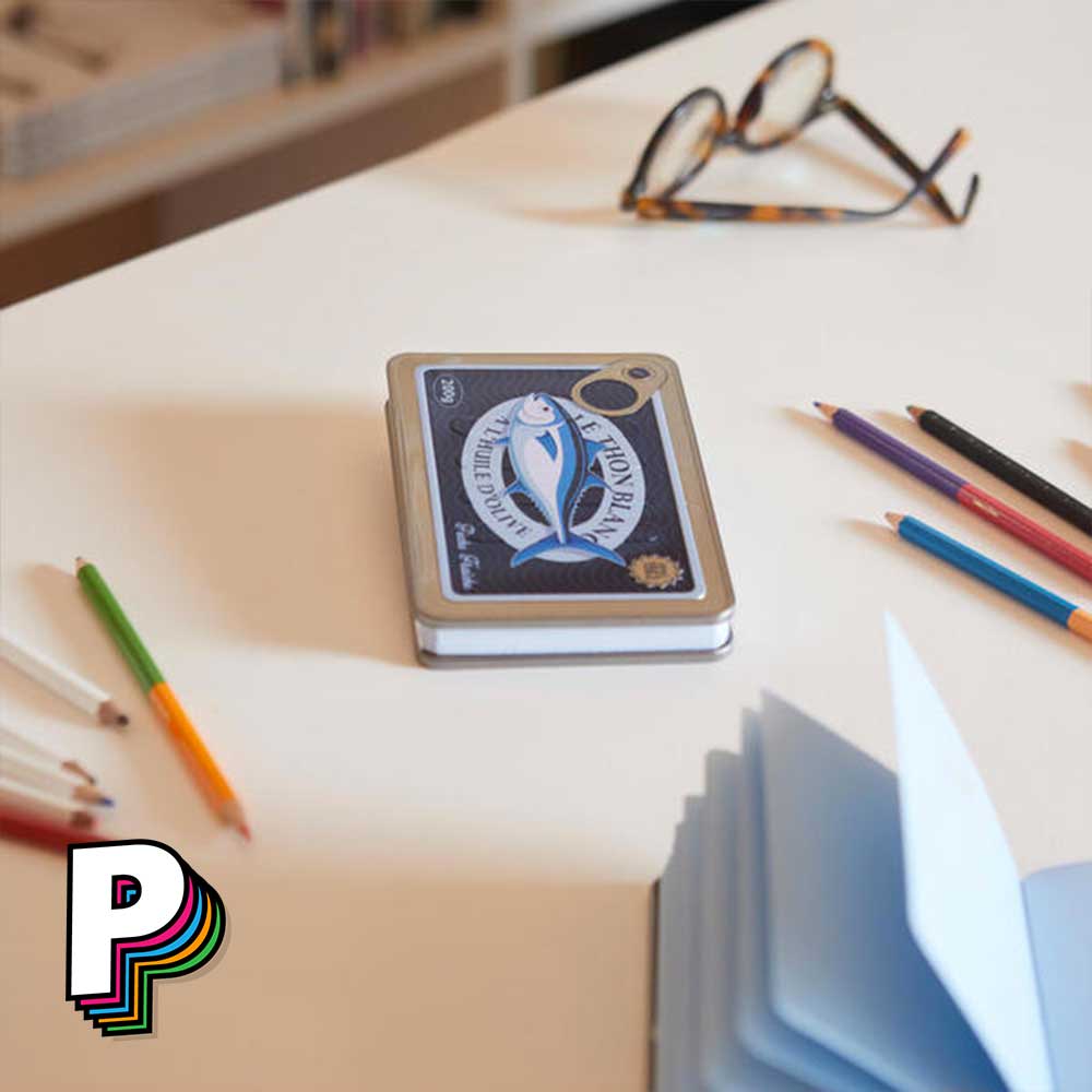 Carnet en forme de boîte de thon conserverie avec pages bleues sur table bureau