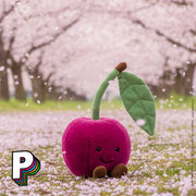 Peluche Cerise Amuseables de Jellycat dans un champ de cerisiers