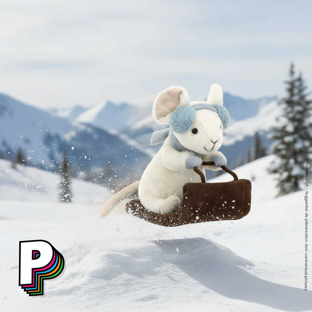Peluche souris Merry en luge de Jellycat entrain de faire un saut sur une bosse piste de ski