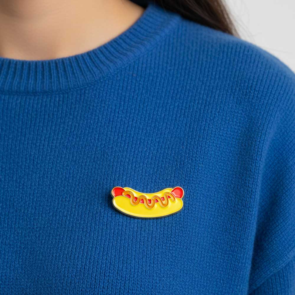 Pin’s Hot-Dog Moutarde sur un pull bleu